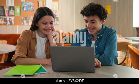 Two students friends Caucasian girl female schoolgirl boy guy male schoolboy together studying learning online laptop internet class lesson prepare Stock Photo