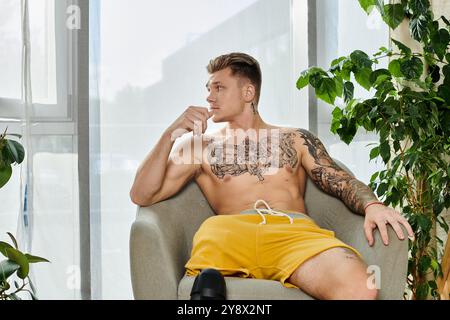 A handsome young man with a prosthetic leg sits thoughtfully in a bright, cozy space. Stock Photo