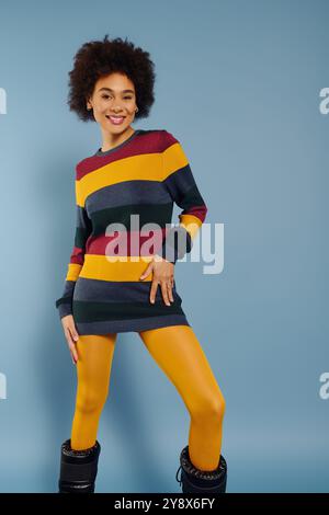 A young woman with a brilliant smile showcases her colorful fashion, radiating happiness. Stock Photo
