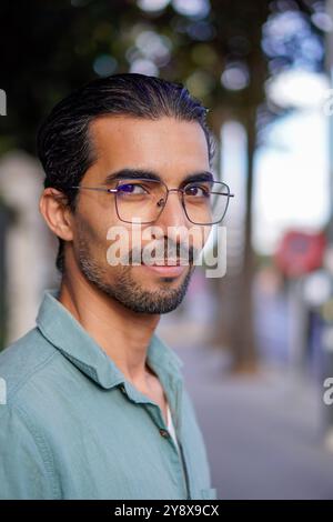 a man portrait looking at camera  with a short smile and wearing sun glasses Stock Photo