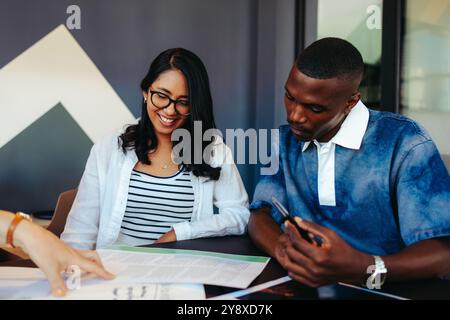College students collaborate in a modern learning environment, exchanging ideas and focused on project work. Stock Photo