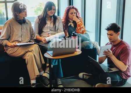 A diverse group of college students in a library working together on a study project, illustrating teamwork and collaboration. Stock Photo