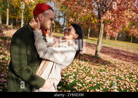 A warm and loving couple enjoys a joyful moment surrounded by vibrant autumn foliage. Stock Photo