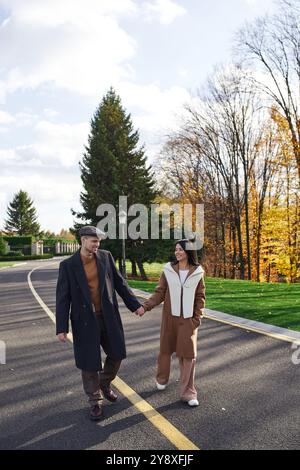 A loving couple walks hand in hand through a park, enjoying a sunny ...