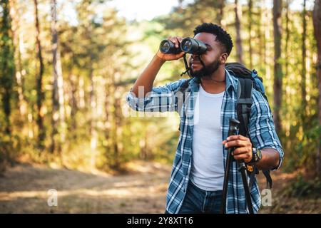 Young man enjoys using binoculars and hiking in nature. Stock Photo