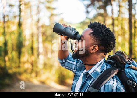 Young man enjoys using binoculars and hiking in nature. Stock Photo