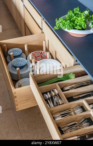 Plates, bowls and cutlery storage in designer kitchen, Gloucestershire, England, UK Stock Photo