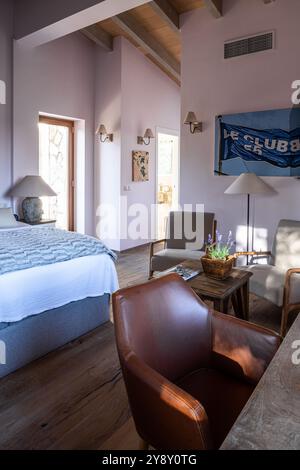 Brown leather armchair with 'le club 55' artwork in bedroom of Spanish villa, Mallorca. Stock Photo