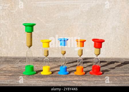 Three hourglasses on rustic weathered wooden table. Time is running Stock Photo