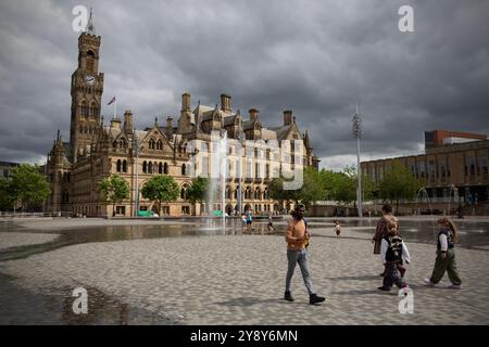 People stroll through Centenary Square in the shadow of Bradford City Hall in the city of Bradford in West Yorkshire which is preparing to become the Stock Photo