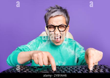 Photo portrait of pretty retired female press typing keyboard webcam annoyed wear trendy green outfit isolated on violet color background Stock Photo