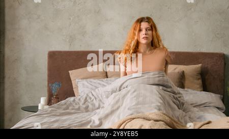 Caucasian woman suddenly wake up abruptly on bed in morning afraid about late time hurry to work hurrying student girl overslept panic lateness waking Stock Photo