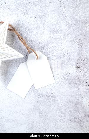 White blank paper tag on craft gifts boxes and Christmas decor on grey conkrete background. Christmas greeting card mockup. Stock Photo