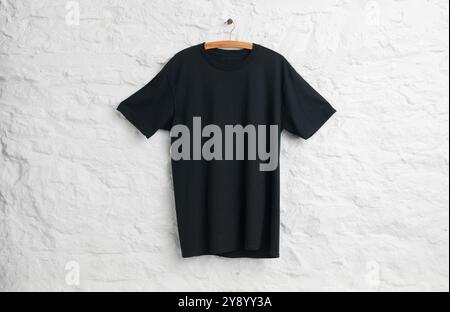 Black teeshirt hanging in front of white painted stone wall Stock Photo