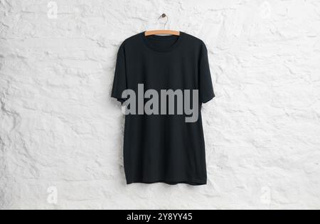 Black teeshirt hanging in front of white painted stone wall Stock Photo