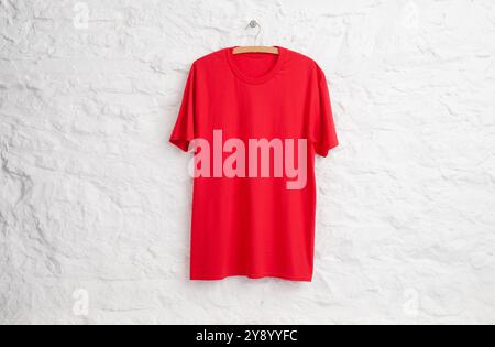 Red teeshirt hanging in front of white painted stone wall Stock Photo