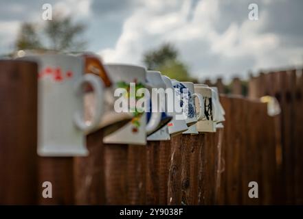 Old ceramic cups on wooden fence in summer cloudy blue sky day Stock Photo