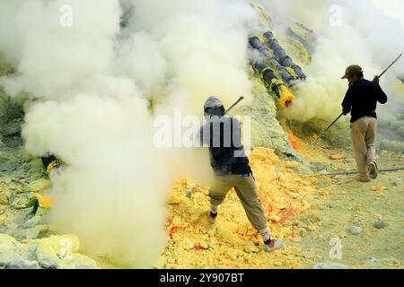 Sulfur miners in the Ijen crater who mine manually without being equipped with standard safety equipment are very risky. Stock Photo