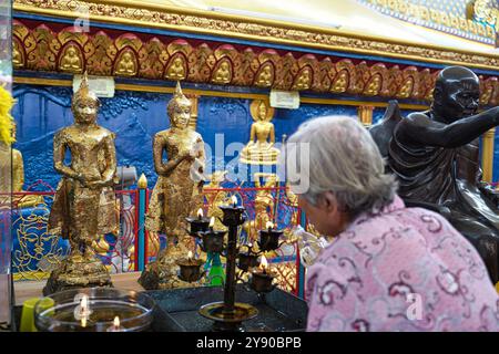 George Town,Penang,Malaysia,April 29,2019-An elderly lady replenishes the oil lamps offered to the Buddha at the Wat Chaiyamangkalaram Buddhist temple Stock Photo