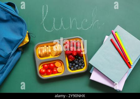 Lunch box with tasty food and school backpack on chalkboard Stock Photo