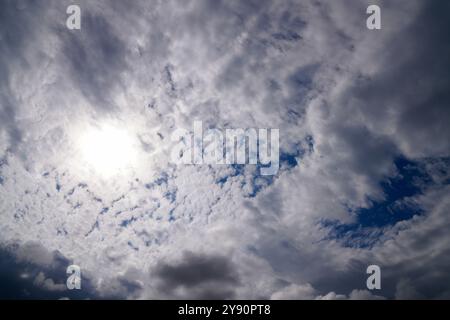A dramatic sky with thick clouds partially covering the sun, creating a captivating play of light and shadows. Stock Photo