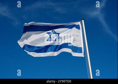 The flag of Israel flutters in the wind against a blue cloudless sky Stock Photo
