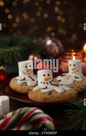 Funny marshmallow snowmen, cookies and festive decor on table Stock Photo