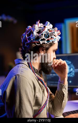 IT admin coding and using EEG headset to upload brain into computer, gaining immortality. Neuroscientist engineering transhumanism experiment, inserting consciousness into cyberspace Stock Photo