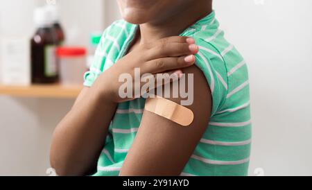 Vaccine and child with plaster on arm, medical shoulder injection dose and immunization bandage. Corona virus immunity, immune system cure or wellness Stock Photo