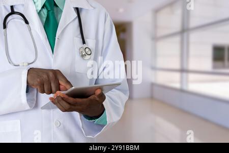 Doctor typing on his touchpad at hospital and copy space. Black man or medical worker Stock Photo