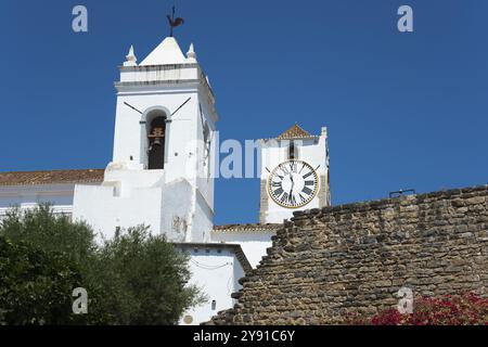 Two church towers with clocks, a wall in the foreground against a bright blue sky, Santa Maria do Castelo church, Tavira, Faro, Algarve, Portugal, Eur Stock Photo