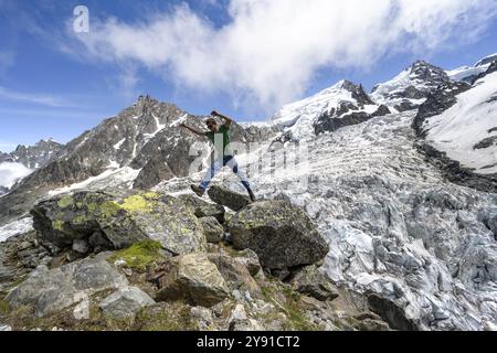 Mountaineer jumping from rock to rock, high alpine glaciated mountain landscape, La Jonction, Glacier des Bossons meets Glacier de Taconnaz, summit of Stock Photo