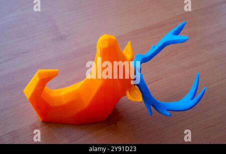 Art object printed on 3D printer. Abstract toy model orange deer with blue horns lying on the table and created on 3d printer. FDM. Concept 3D Printing. Additive modern new progressive technologies Stock Photo