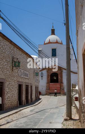 Mineral de Pozos, Guanajuato, México; 04 18 2024; A street in the magical town of Mineral de Pozos with a white church at the back. Stock Photo