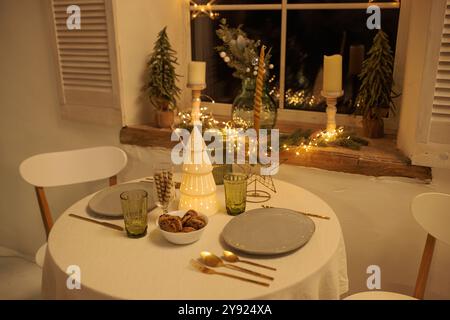 Cozy Christmas setting with a round table near the window, The table is decorated with a decorative Christmas tree in the center, Soft lighting from c Stock Photo