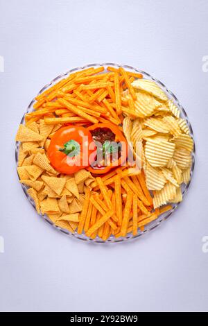 A vibrant snack platter featuring a variety of chips and dips, presented in a decorative bell pepper bowl Stock Photo