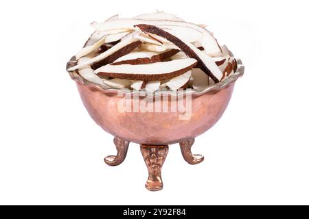 Freshly sliced coconut pieces in a traditional copper bowl, perfect for tropical food concepts. Stock Photo