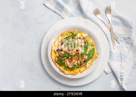 Homemade egg omelet with champignons and arugula and herbs on white kitchen table Stock Photo