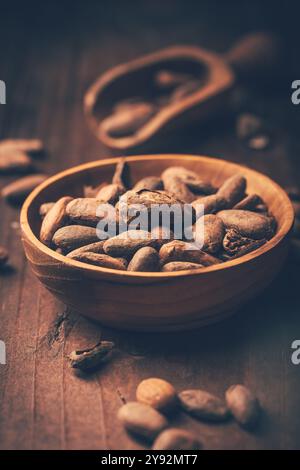 Organic cocoa beans in wooden bowl on wooden background Stock Photo