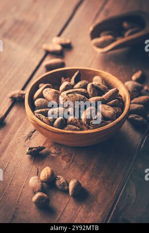 Organic cocoa beans in wooden bowl on wooden background Stock Photo
