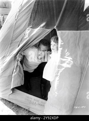 TONY CURTIS and his daughter JAMIE LEE CURTIS in umbrella tent on set location candid in Salta, Argentina during filming of TARAS BULBA 1962 director J. LEE THOMPSON novel Nikolai Gogol screenplay Waldo Salt and Karl Tunberg music Franz Waxman Harold Hecht Productions / Curtleigh Productions / Avala Film / United Artists Stock Photo