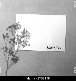 White paper with flowers shadow and words "Thank You" written on it. The paper is hanging on wall. Thank you message for presentation or business Stock Photo