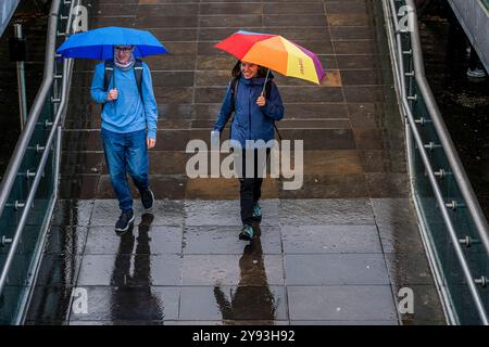 London, UK. 8th Oct, 2024. Crossing the Millennium Bridge in the rain - The unsettled Autumn continues, but tourists seem to be unperturbed as they roam the sites - Wet weather continues to hit London. Credit: Guy Bell/Alamy Live News Stock Photo