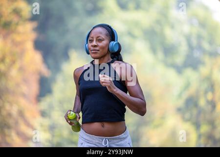 Woman listening to music with headphones while jogging in the park Stock Photo