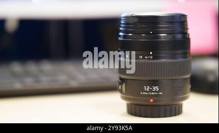 A close-up of a camera lens with detailed markings, resting on a reflective surface against a blurred background. This image highlights the precision Stock Photo