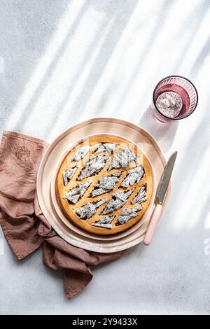A dragon fruit topped cake served with a pink glass on a sunny day, with distinct geometric shadows cast over a textured surface Stock Photo