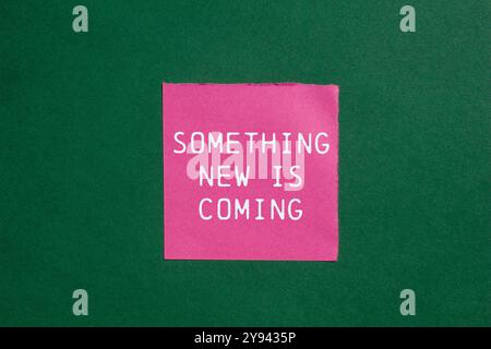 Something new is coming message written on ripped torn pink paper on green background. Conceptual something new is coming symbol. Copy space. Stock Photo