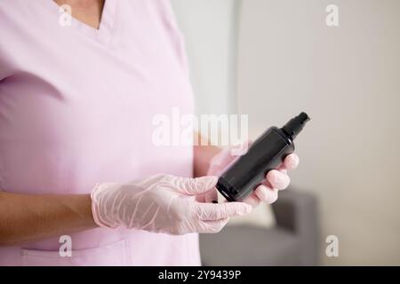 Cropped image of a female massage therapist's hands as she prepares a bottle of massage oil, highlighting the attention to detail and cleanliness in a Stock Photo