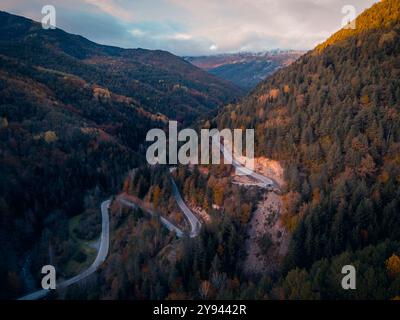 Aerial view of a winding serpentine road cutting through the lush green ...