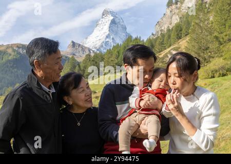 A Korean family, spanning three generations, enjoys a scenic autumn day with the iconic Matterhorn mountain as a backdrop in Zermatt, Switzerland Stock Photo